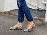 A person wearing blue jeans and navy ballet flats with a multicolored design on the shoe's surface. Comfortable European women's shoes.