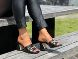 Classy European women's sandals with gold bit detail. Mule style on chunky block heel. Wedding or special occasion slide. In black.
