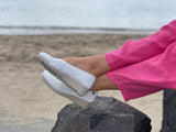 A person wearing a pair of white Aerobics Lockheed 1 ballet shoes with a contoured insole and a lightweight rubber sole . Quality European women's footwear made from soft leathers.