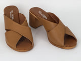 A person wearing Via Nova Hanky sandals in tan color, with enough space to insert a foot not shown, v throat with crossover straps and block heel. Comfortable footbed.