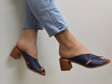 A person wearing Via Nova Hanky sandals in navy color, with enough space to insert a foot not shown, v throat with crossover straps. Comfortable footbed.