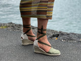 A person wearing Via Nova Flynn sandals in khaki green color. European Espadrille women's sandals with enclosed heel and toe. Woven wedge heel, lace up straps. Comfortable footbed. Made in Spain.